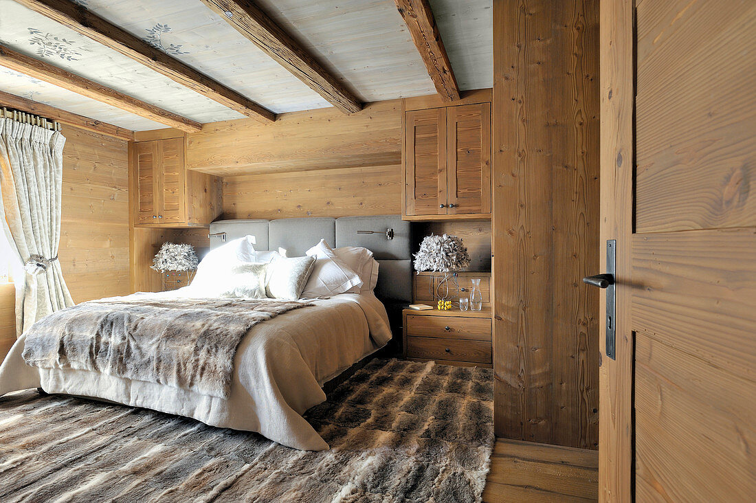 Rustikales Schlafzimmer mit Fellteppich und Holzverkleidung