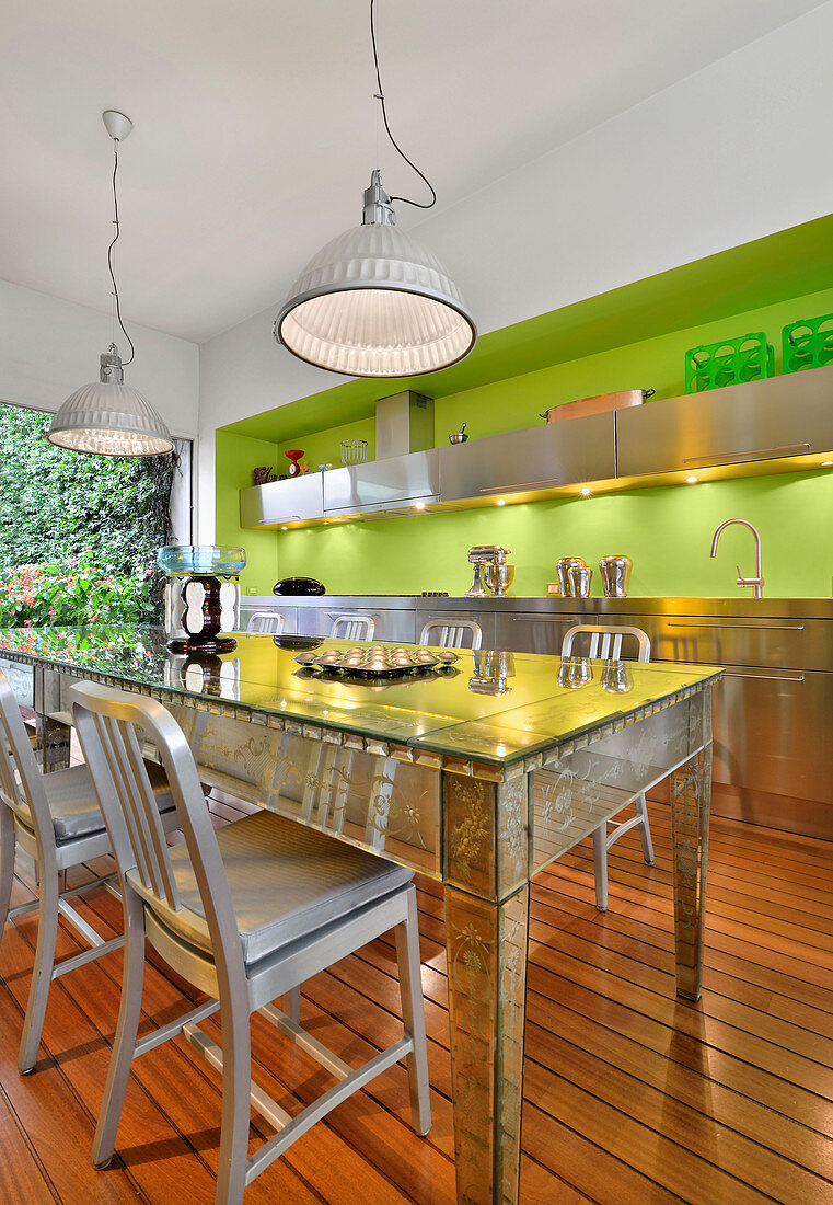 Verspiegelter Tisch in der Küche mit Edelstahlfronten und grüner Wand