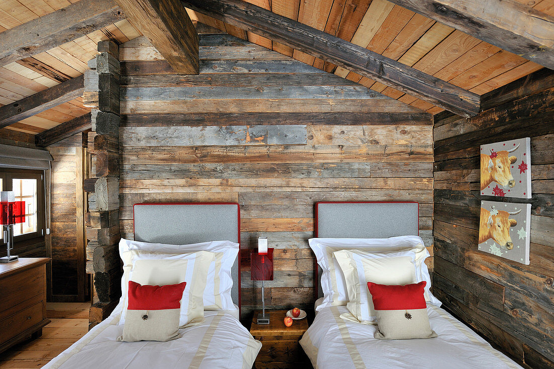 Zwei Einzelbetten im rustikalen Schlafzimmer mit Holzwänden