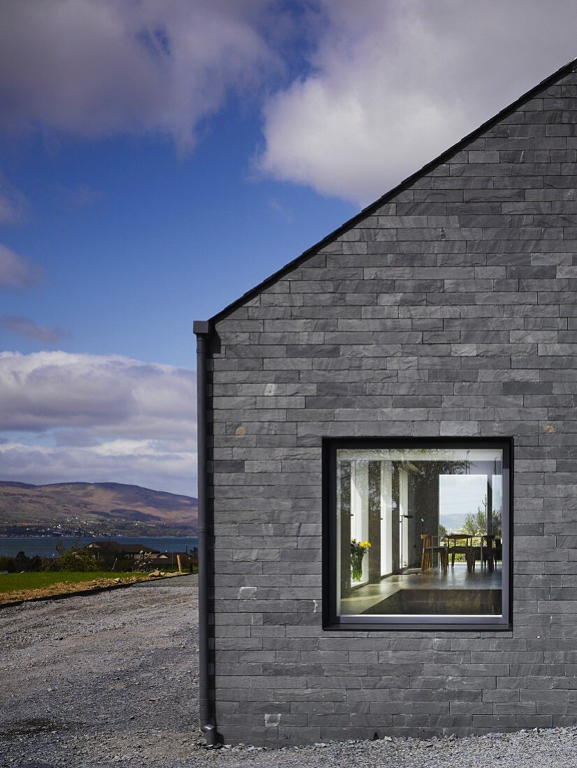 Graue Steinfassade eines modernen Hauses, Blick durchs Fenster