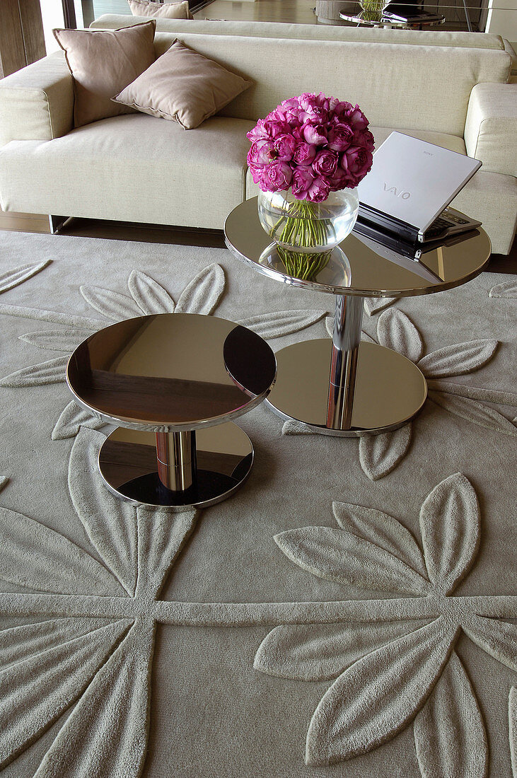 Zwei runde glänzende Beistelltische auf Teppich mit Blumenrelief