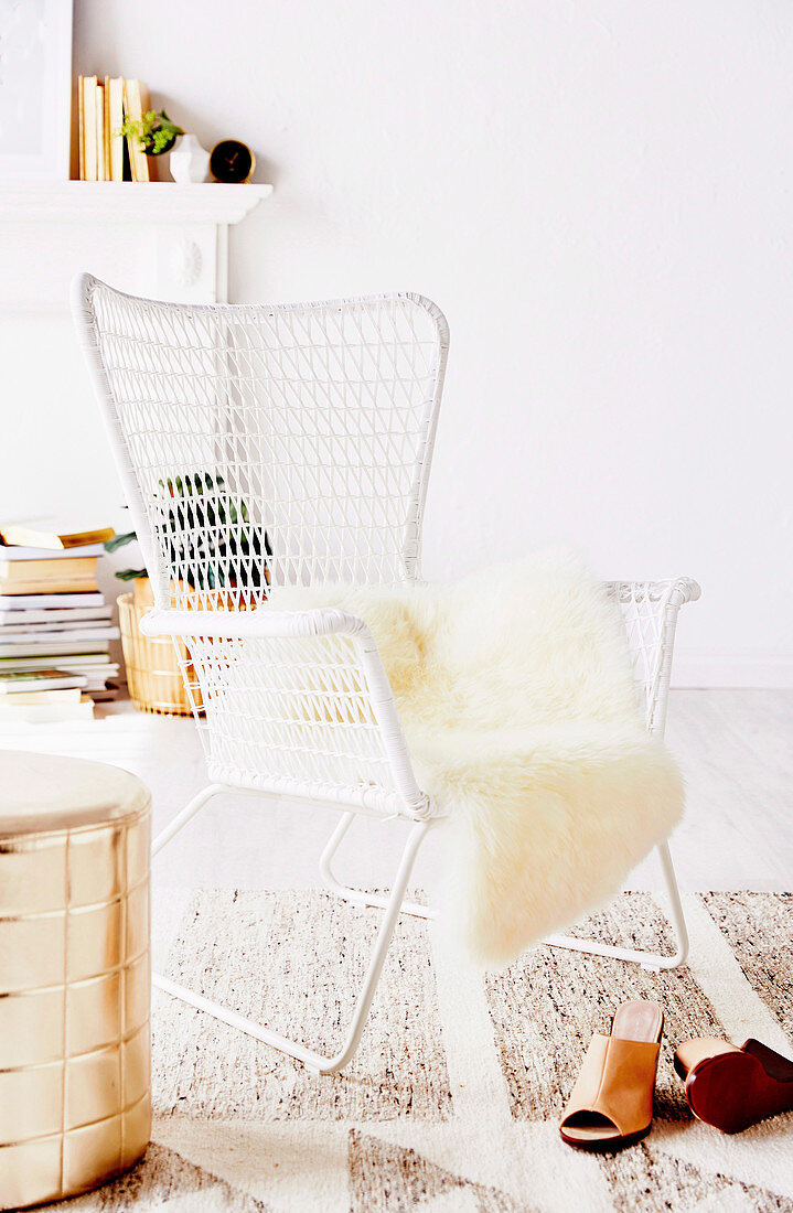 White outdoor chair with fur cover and pouf in gold colors