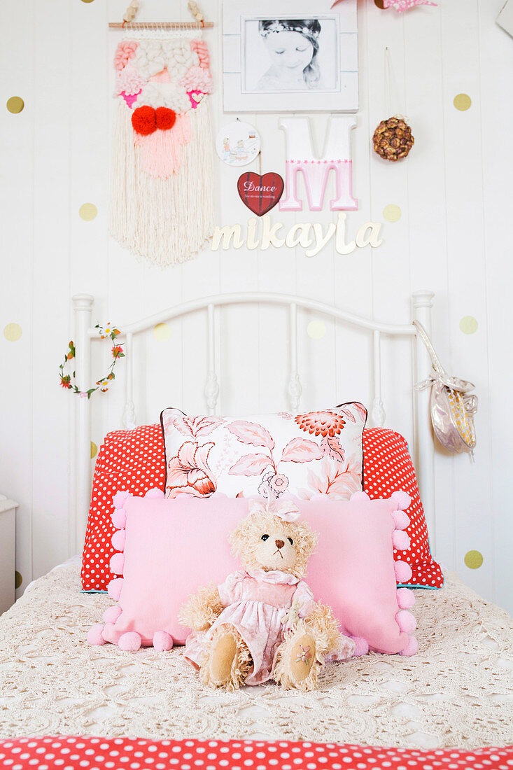 Weißes Bett mit Kissen und Kuscheltier im Mädchenzimmer