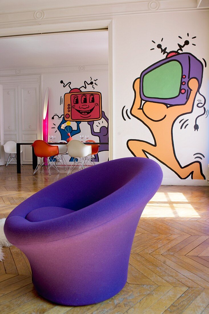 Runder, blauer Sessel vor Pop Art Gemälde an der Wand