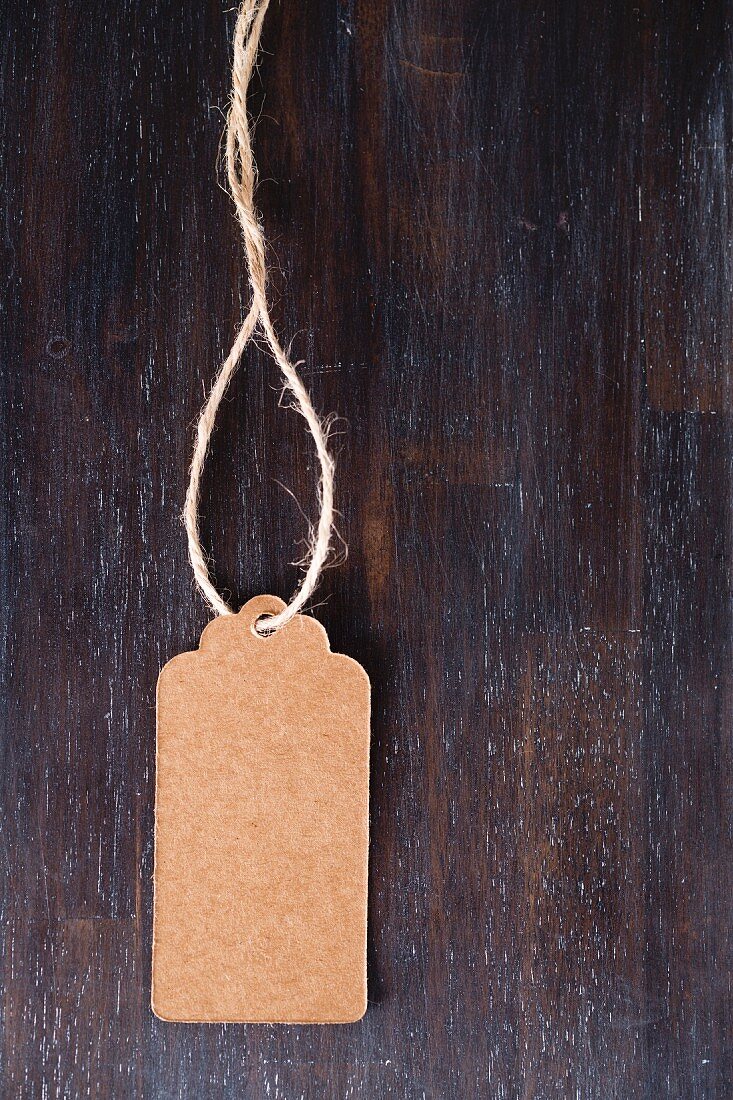 Braunes Papieretikett mit Schnur auf dunklem Holz