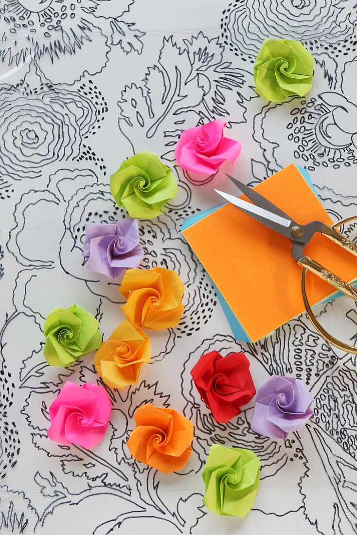 Röschen aus Papier auf einer Folie mit aufgemaltem Blumenmuster