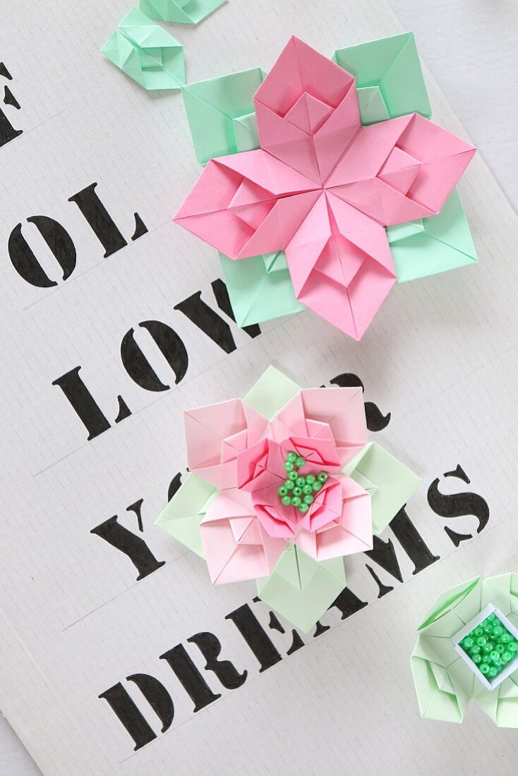 Origamiblumen auf mit Buchstaben bedrucktem Papier