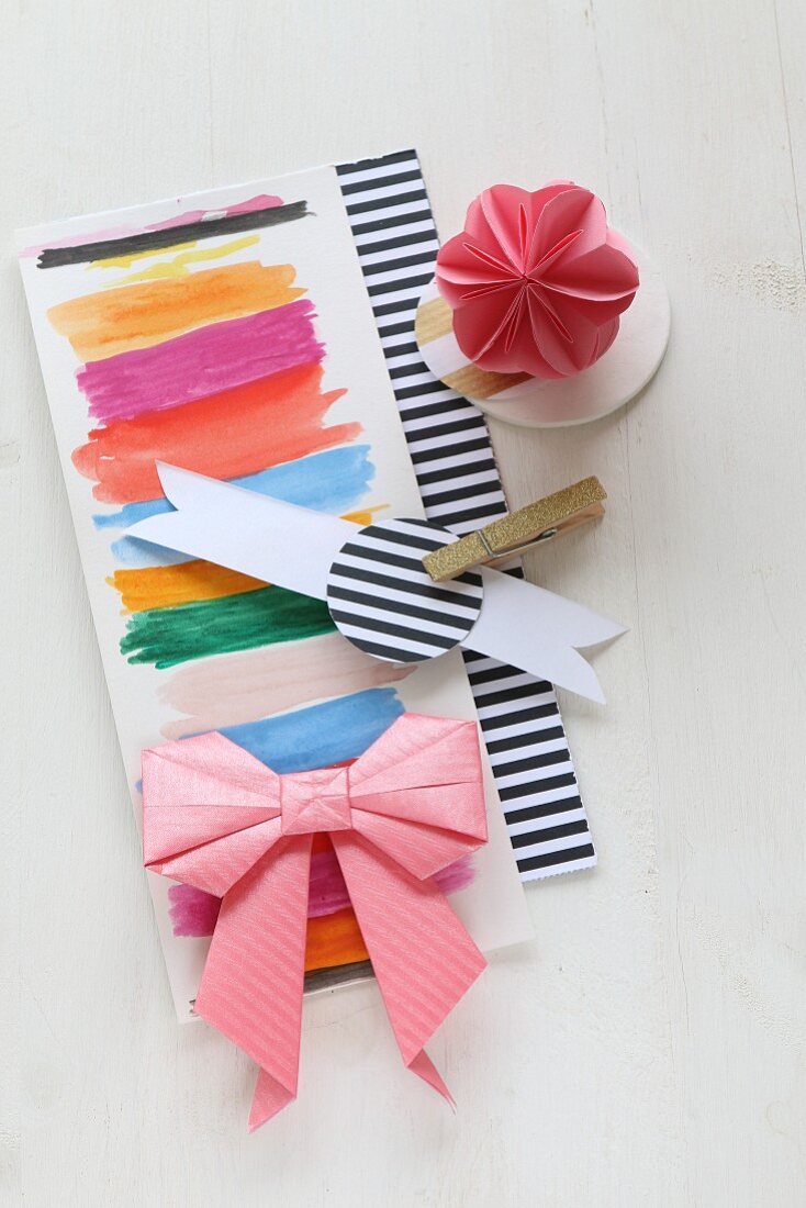 Origami-Schleife und Blume auf eine Papier mit Farbstreifen