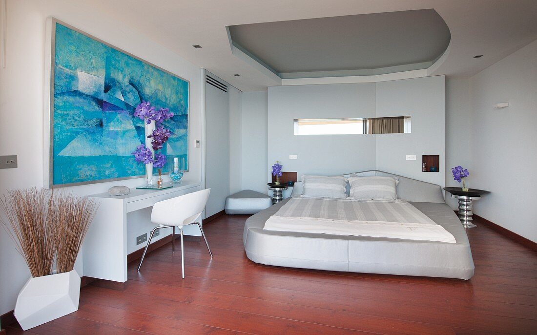 Futuristisches Schlafzimmer mit Polsterbett und abstrakter Kunst