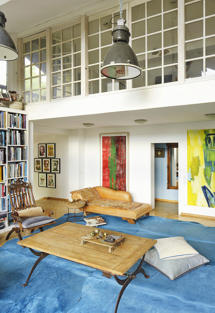 Blick vom Wohnzimmer mit blauem Teppich auf verglaste Galerie