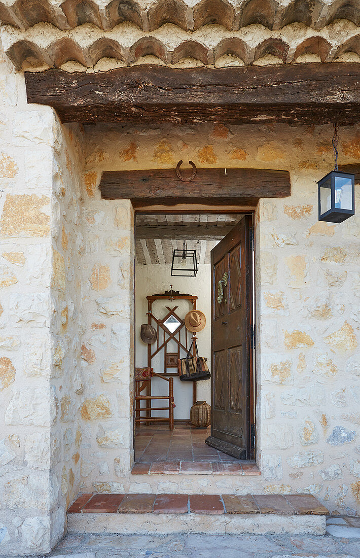 Blick auf geöffnete Holztür eines rustikalen Natursteinhauses