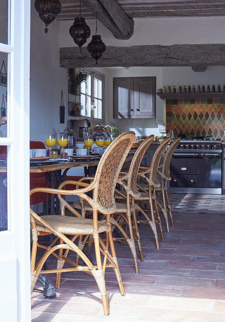 Blick von der Terrasse in Speisesaal mit gedeckten Frühstückstischen und Vintage Geflechtstühlen