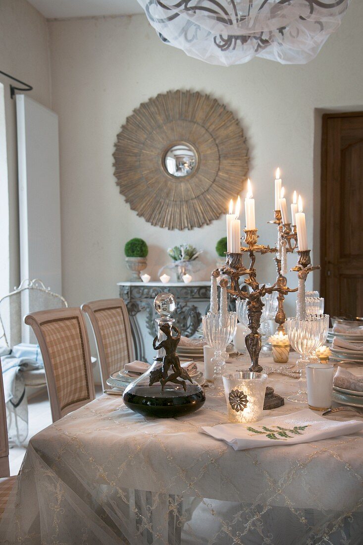 Candelabra on festively set dining table in front of antique mirror on wall