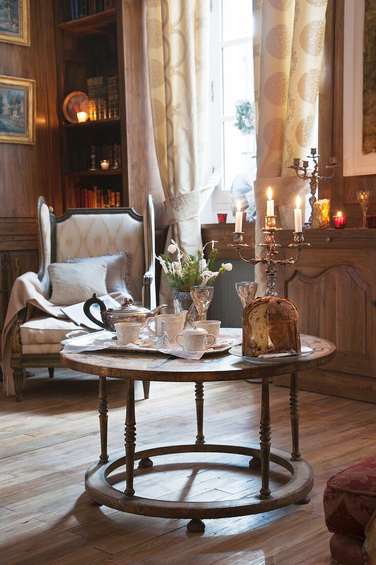 Antiquarischer, runder Tisch mit Teegeschirr, Kerzenständer und Panettone