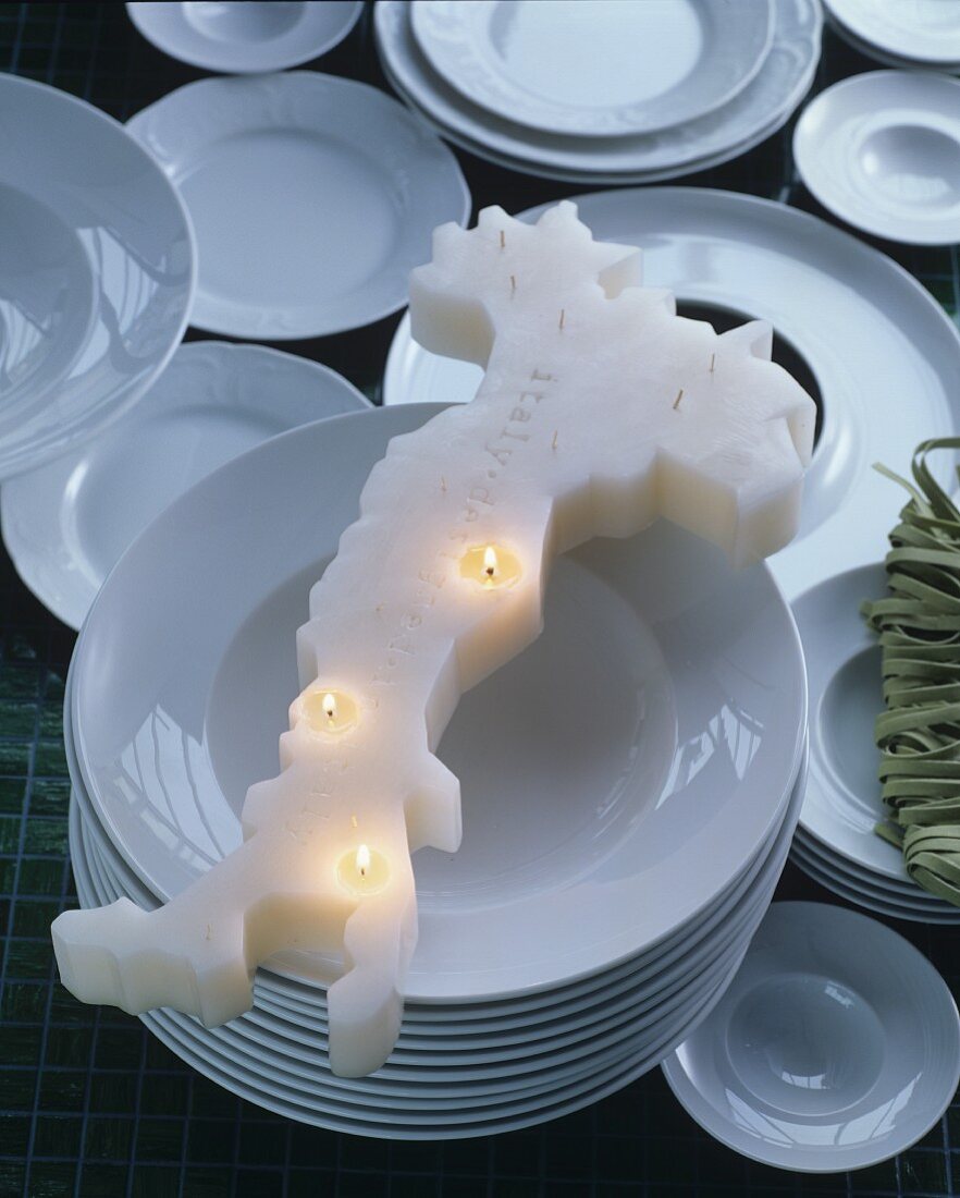 Kerze in Form des italienischen Stiefels auf weißen Tellern