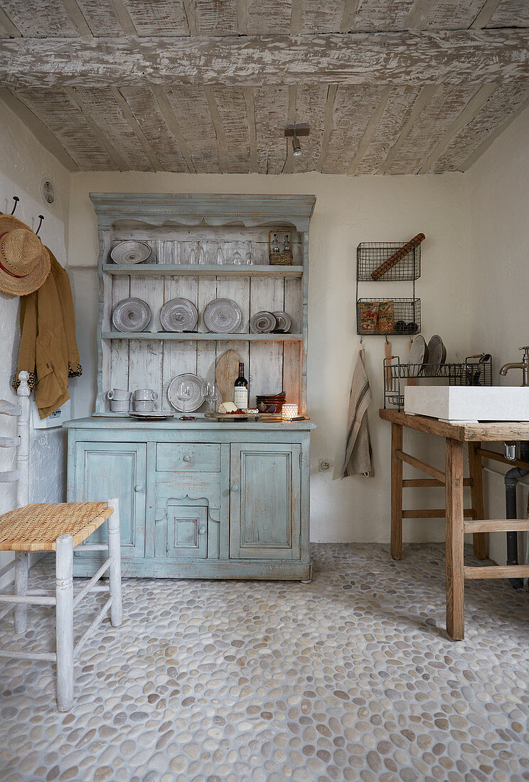 Rustikaler Holztisch mit Spülbecken und Anrichte in kleinem Raum mit Kieselsteinboden