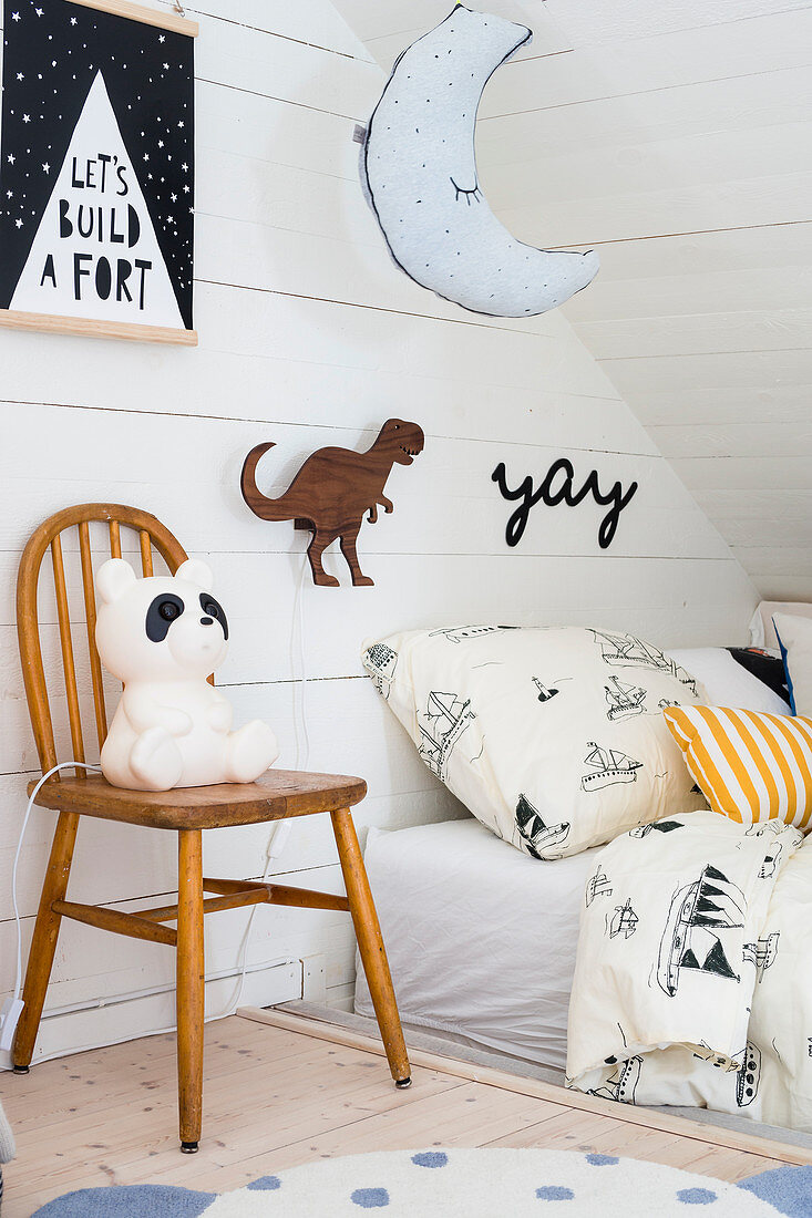 Vintage panda lamp on chair next to bed in child's attic bedroom