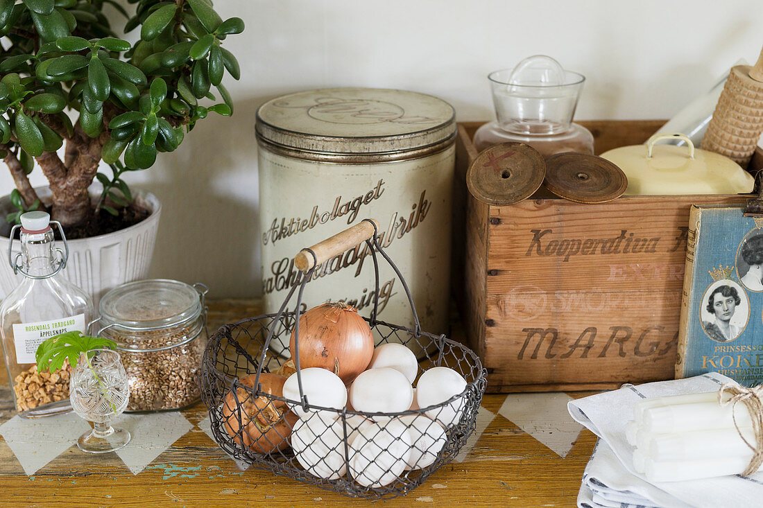 Wire basket of eggs and onions and other old kitchen utensils
