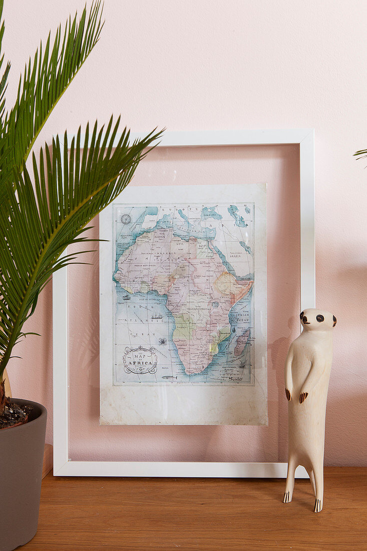 Erdmännchen-Figur vor gerahmter Kontinentkarte