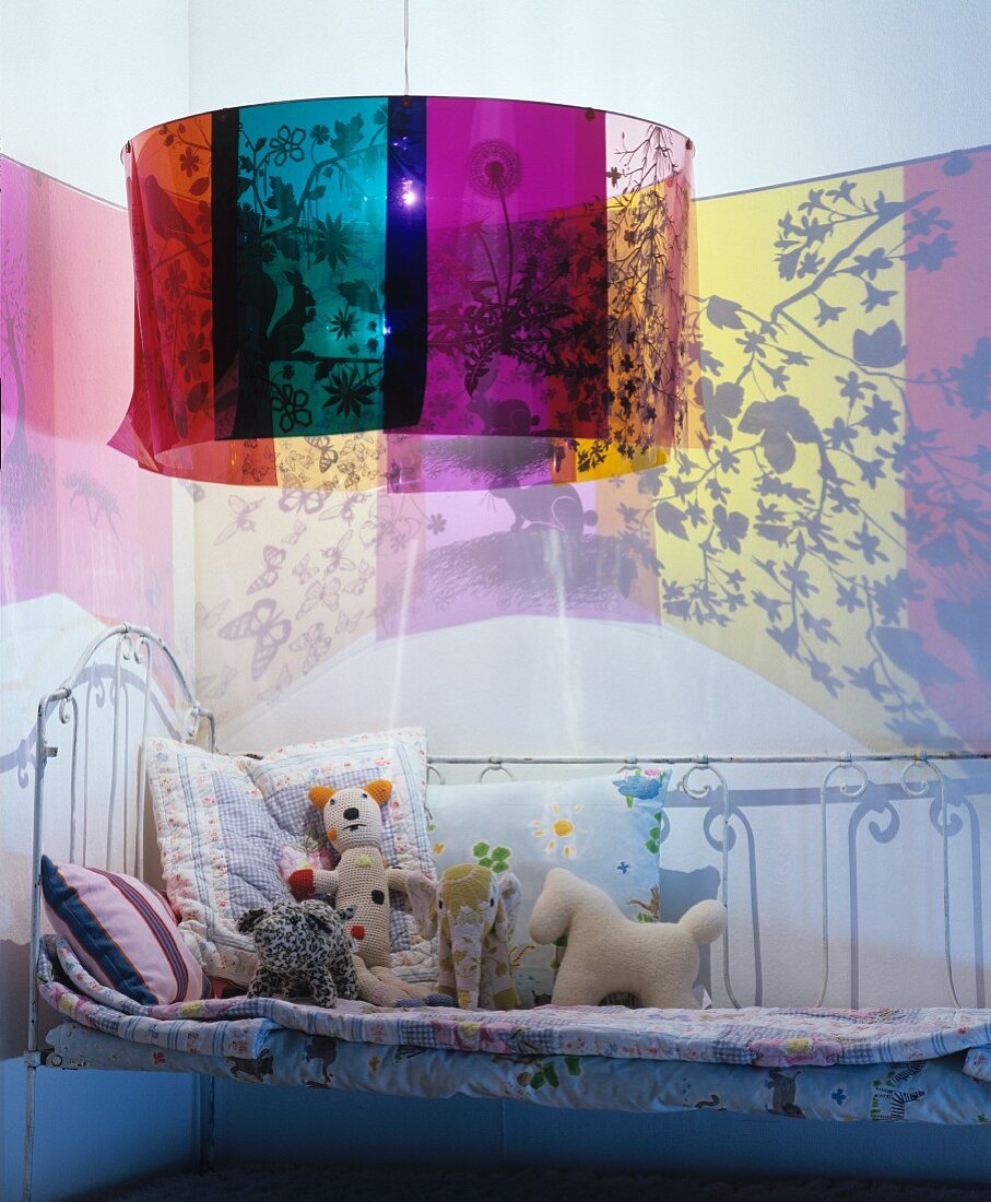 Lamp casting colourful patterns on walls above metal bed in child's bedroom