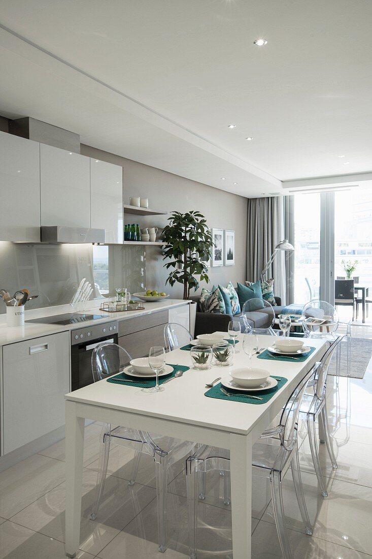 Fitted kitchen and set white dining table in open-plan interior