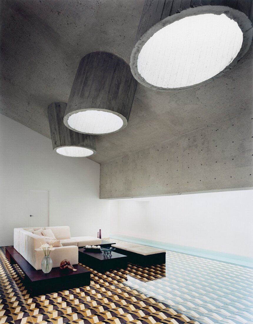 Außergewöhnlicher Loungebereich mit runden Betonoberlichtern und geometrischem Fliesenmuster mit optischer Täuschung