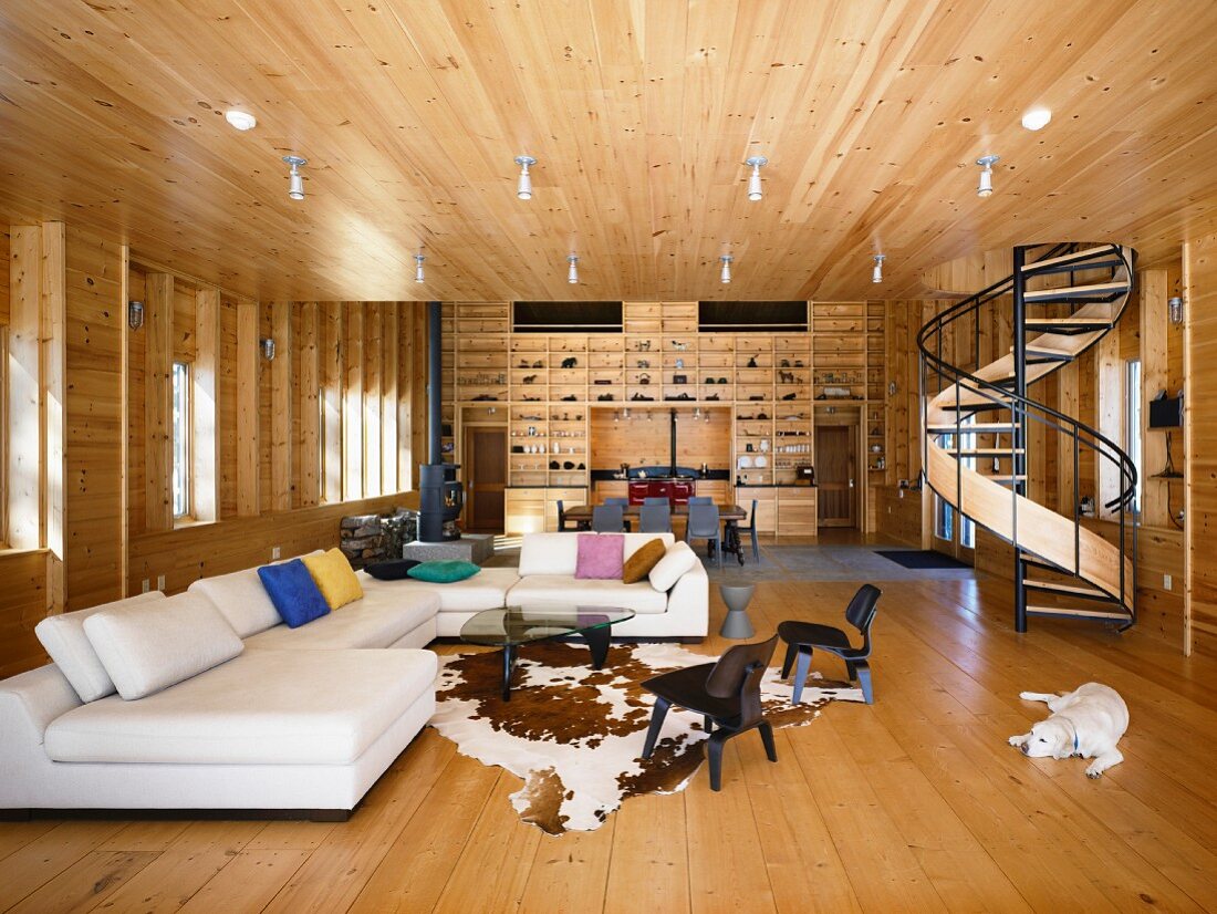 Offener Wohnraum im Holzhaus mit elegantem Loungebereich, Wendeltreppe und Regalwand