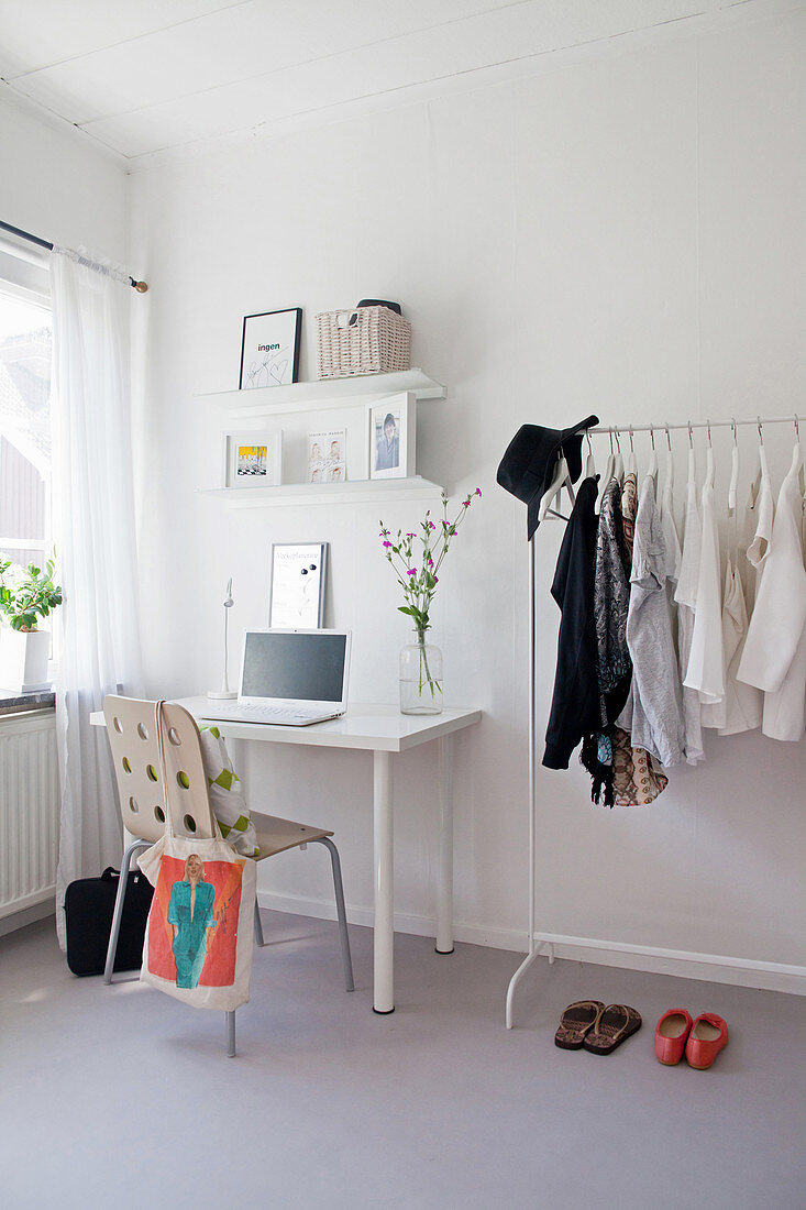 Desk and coat racks in simple room in grey and white
