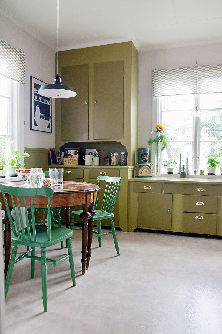 Alter Tisch und Stühle in der Retro-Küche mit olivgrünen Fronten