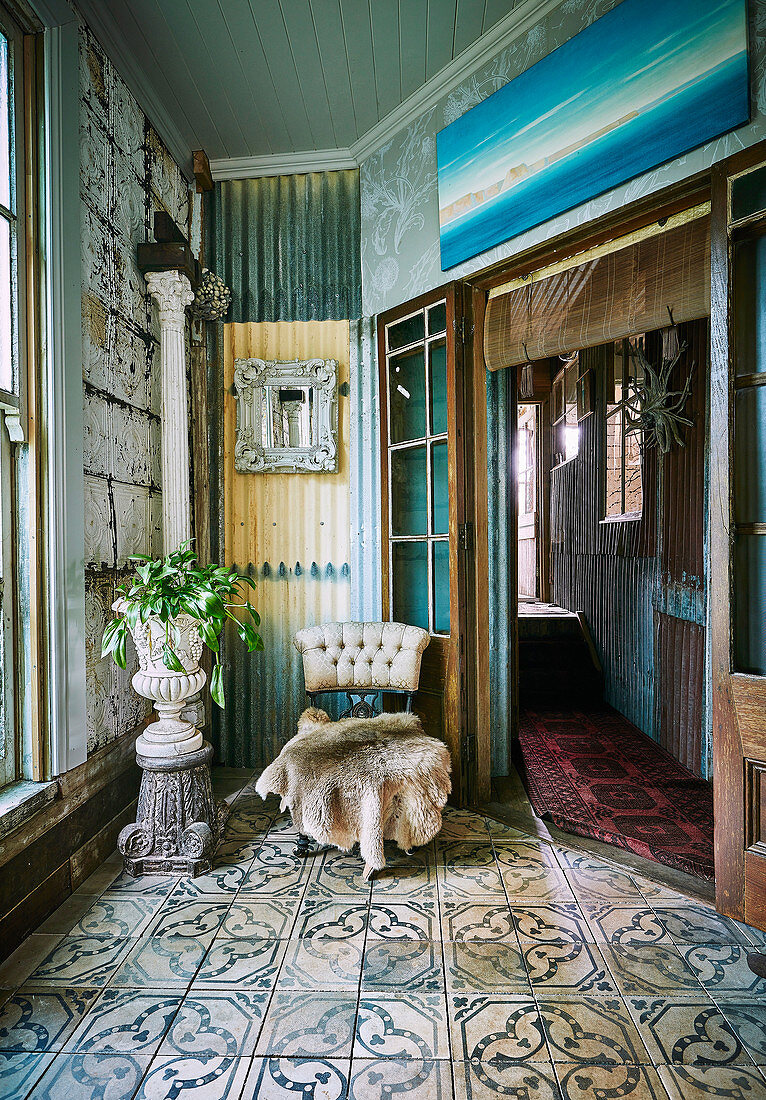 Stuhl mit Tierfell und Amphore mit Zimmerpflanze in Vintage Ambiente mit Ornamentfliesen