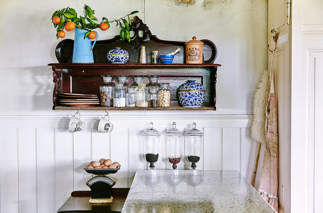 Antik Wandregal mit Porzellangefässen, Aufbewahrungsgläsern und Mandarinenzweig in der Küche