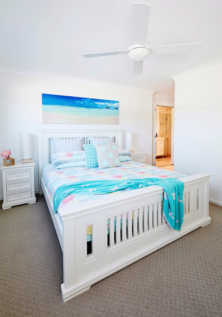 White double bed with wooden frame in a bright bedroom