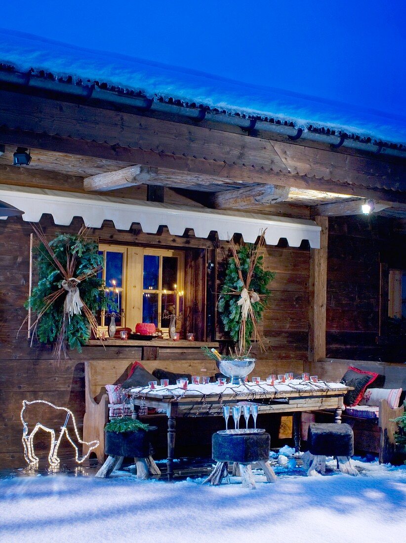Verschneite und dekorierte Chalet-Terrasse mit Beleuchtung in Abendstimmung