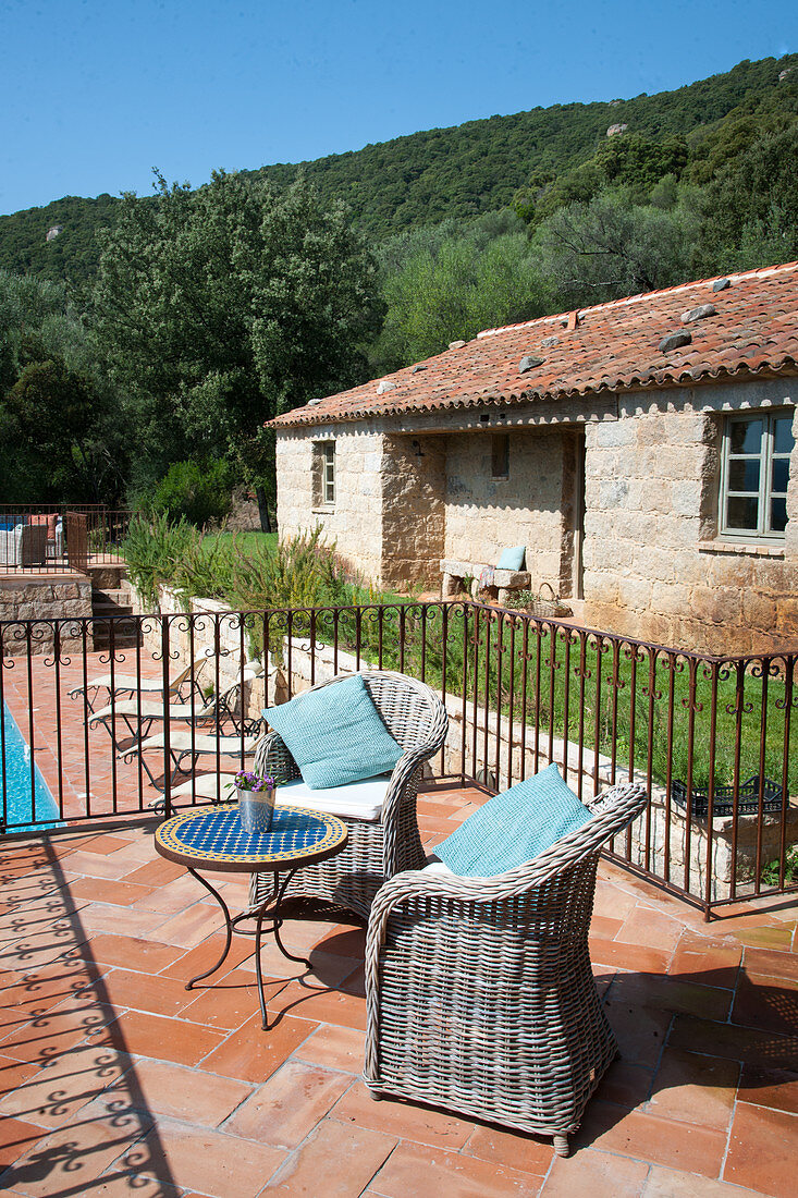 Wicker armchairs on terrace of Mediterranean country house with pool