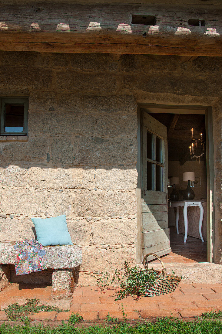 Old stone bench outside Mediterranean stone house with open exterior door