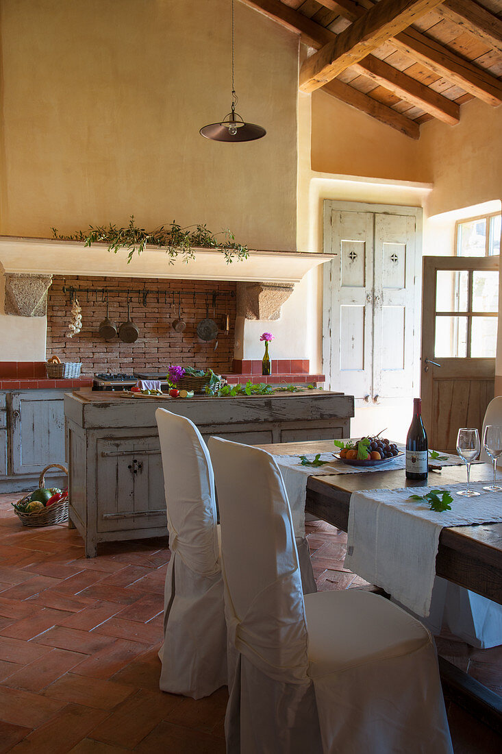 Dining table and loose-covered chairs in Mediterranean country-house kitchen