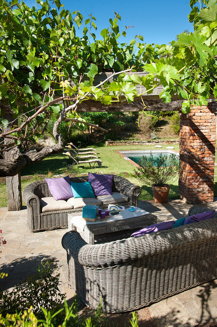 Two wicker sofas under pergola in Mediterranean garden