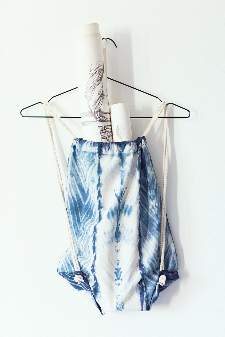 Sports bag hand-dyed with Shibori pattern hung from wire coathanger