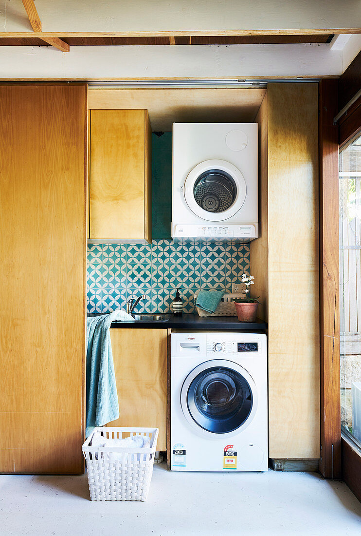 Laundry room behind a sliding door with hanging washing machine