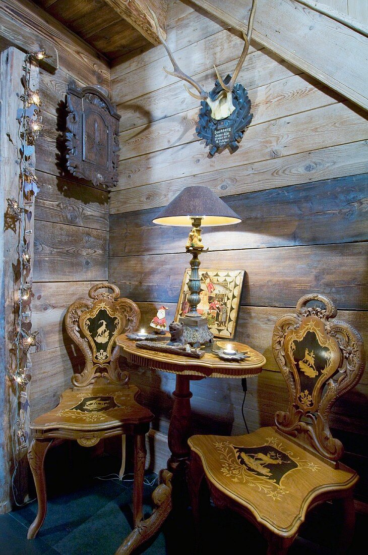 Antike Holzstühle und ein Tischchen vor der Holzwand im Chalet
