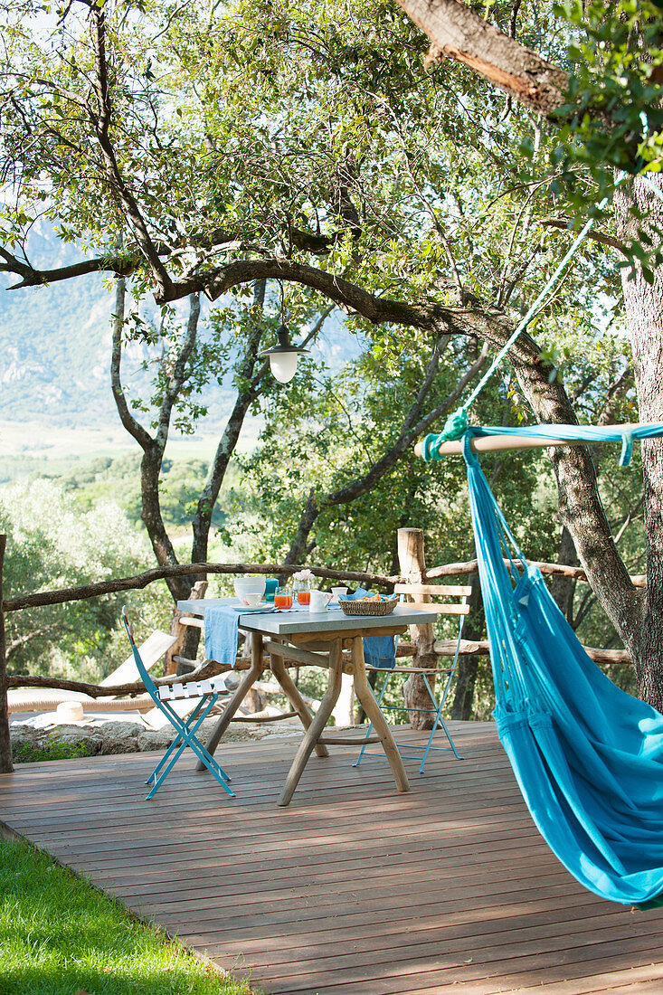 Blue hammock and set breakfast table on wooden terrace