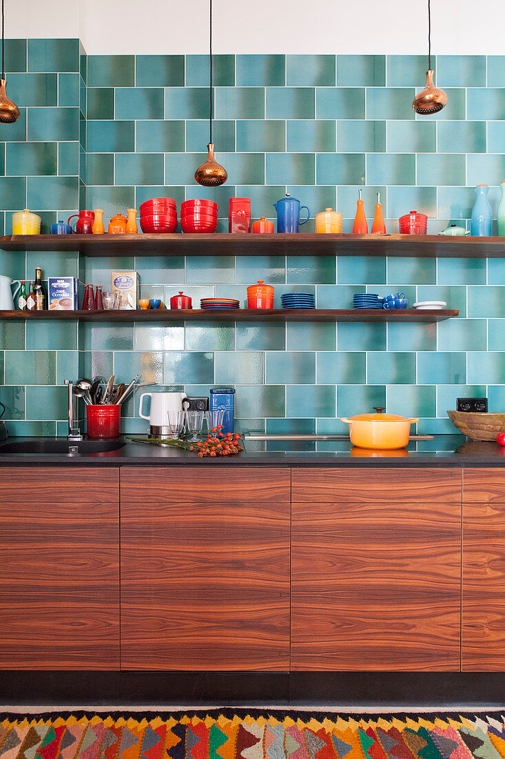 Buntes Geschirr in der Küche mit Holzfronten und blauen Retrofliesen