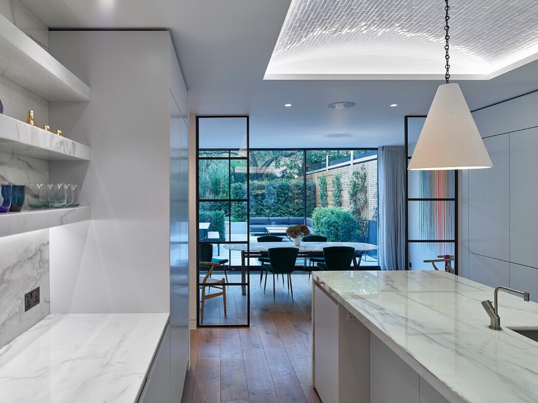 Glass and steel partitions and marble island counter in modern kitchen
