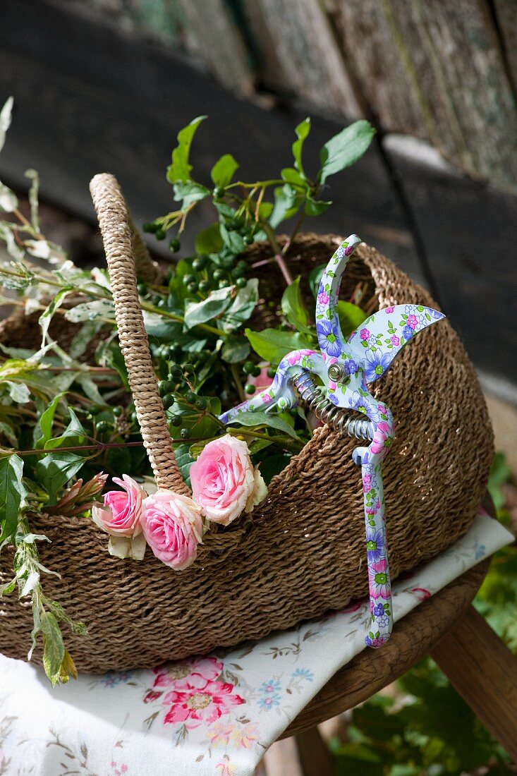 Roses, green branched and secateurs in shopping basket