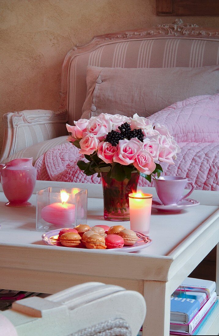 Romantisch gedeckter Couchtisch mit Rosenstrauß und Macarons