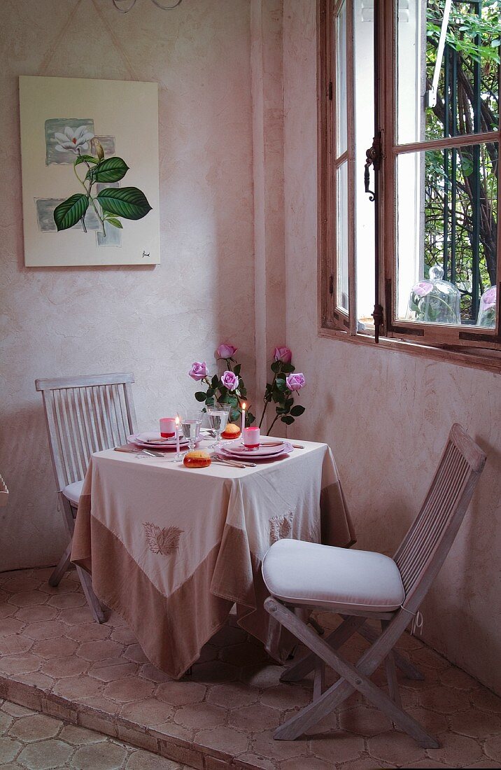 Romantisch gedeckter Tisch unter dem Fenster