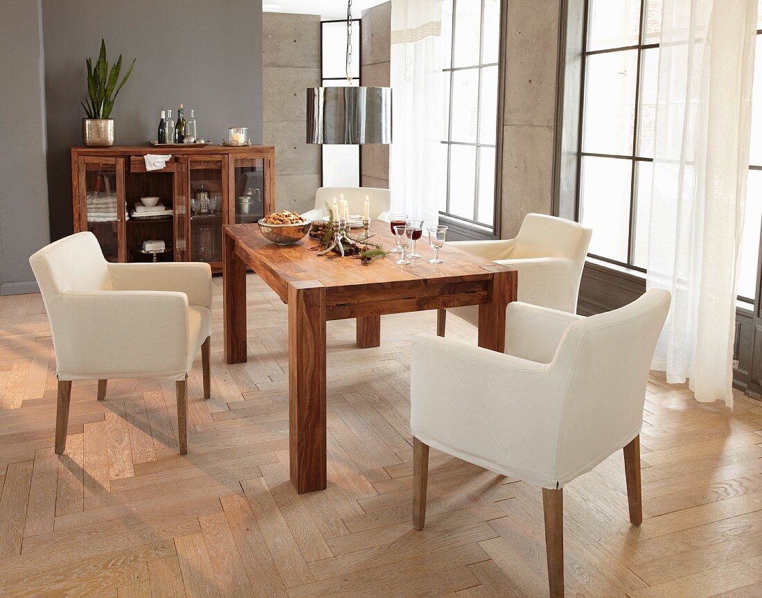 Cream armchairs around Advent arrangement on solid-wood table in modern interior