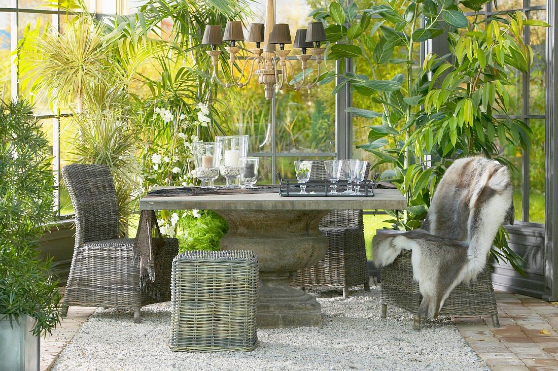 Rattan chairs around solid stone table on gravel floor in conservatory