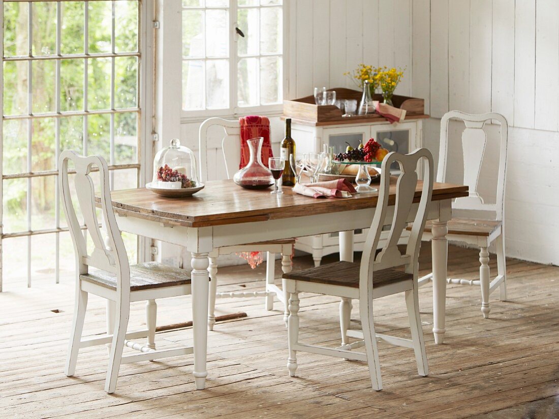 Set dining table in country house with rustic wooden floor and white wood-clad walls