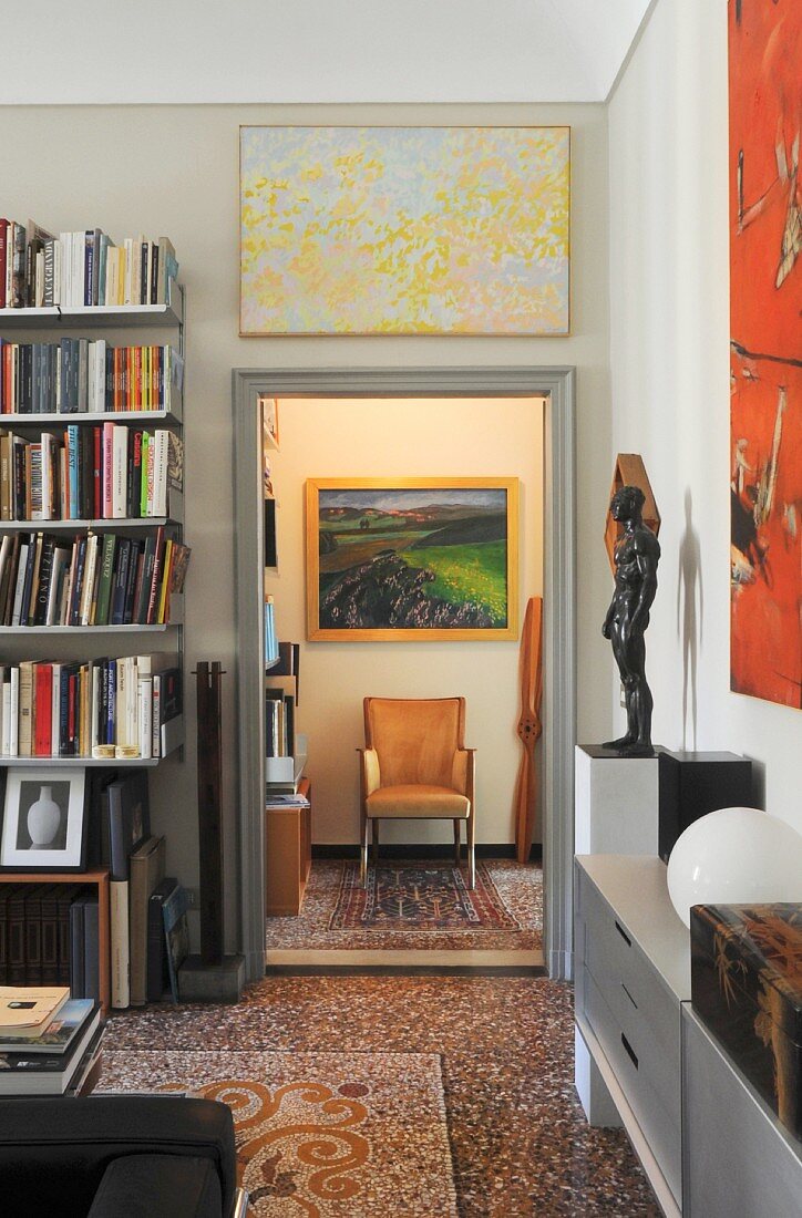 Bookcase and terrazzo floor in elegant living area with view of armchair through open door